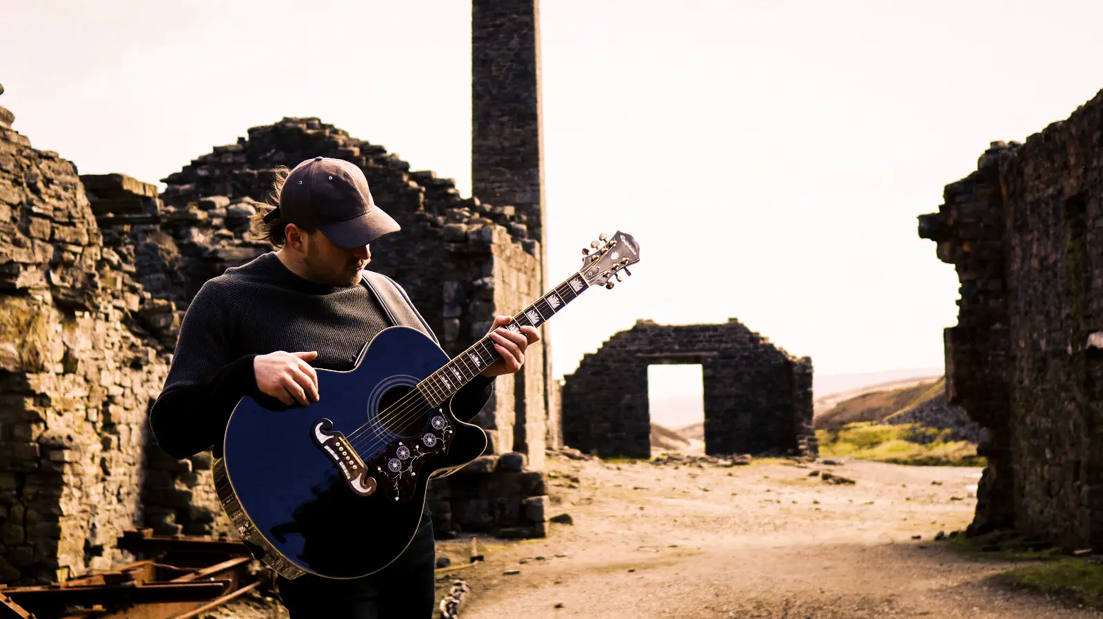 Martin Purvis playing guitar among old mine ruins in the North East of England
